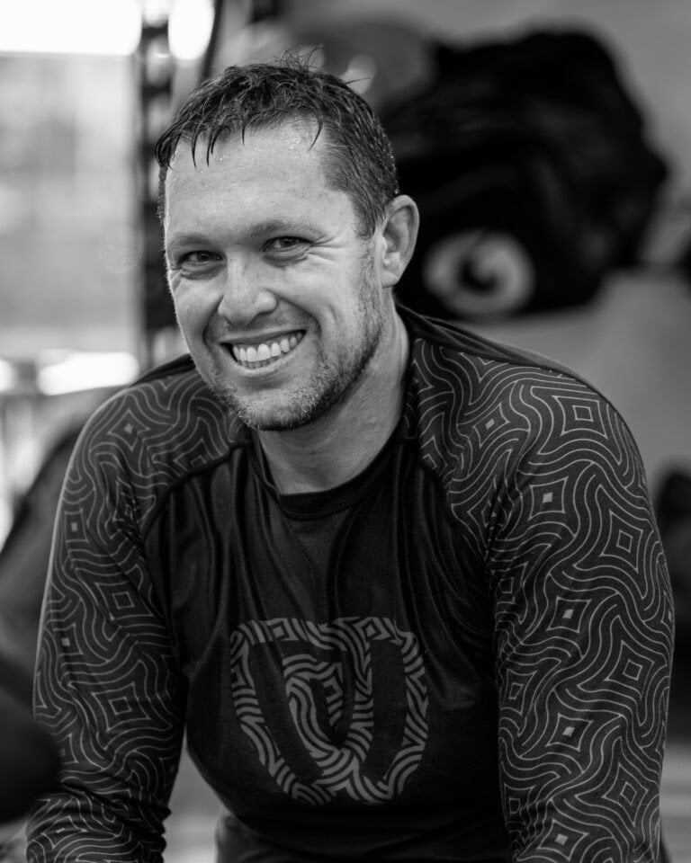A man smiling while sitting on a the mats.