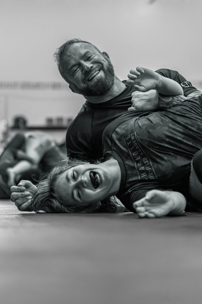 Two people practicing Brazilian jiu-jitsu, one applying a hold on the mat during training.