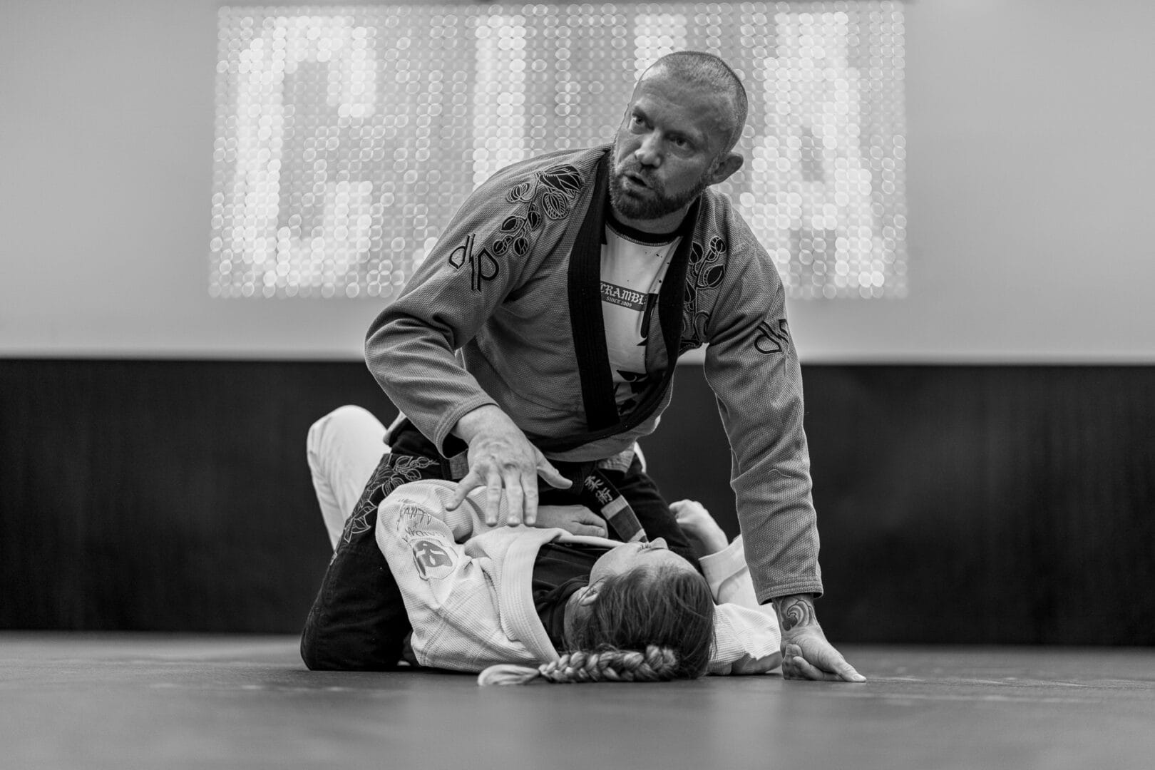 Two individuals practicing Brazilian Jiu-Jitsu on a mat wearing martial arts gis.