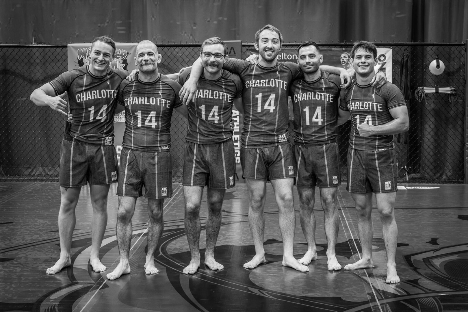 Six male athletes barefoot on an indoor court wearing matching Charlotte uniforms with number 14.